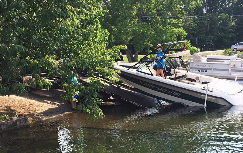 Boat being recovered from the water at a wooded shoreline