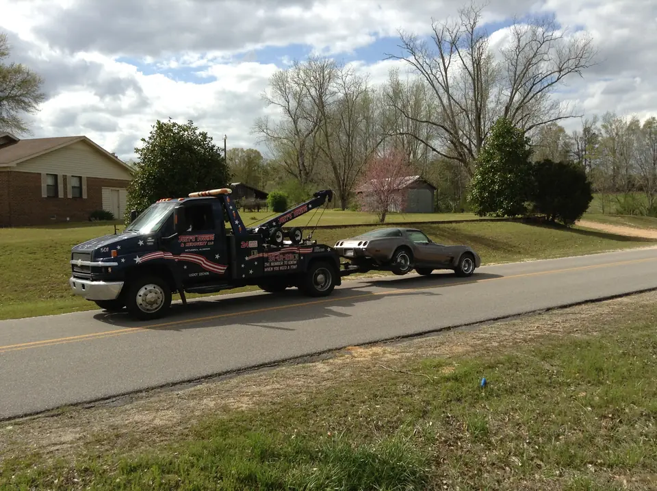 Joey's wrecker towing a classic sports car along a country road