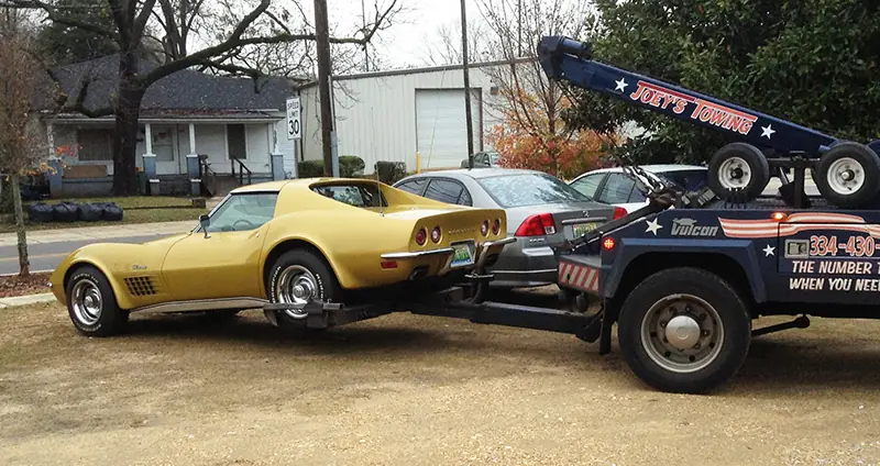 Gold 1970s Corvette lifted on the wheel-lift of Joey's wrecker