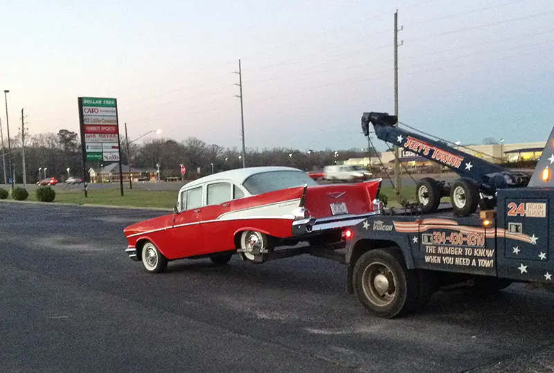 Red 1957 Chevy Bel Air on Joey's wheel-lift in a shopping-center lot