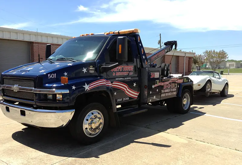 Front of Joey's wrecker number 501 with a white Corvette behind it