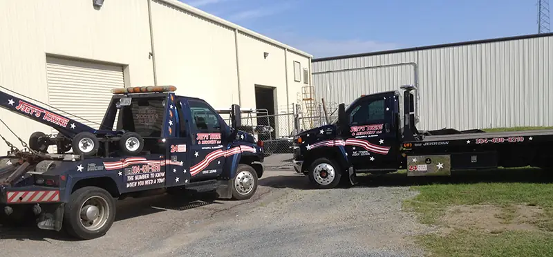 Joey's wrecker and rollback flatbed parked outside a metal shop building